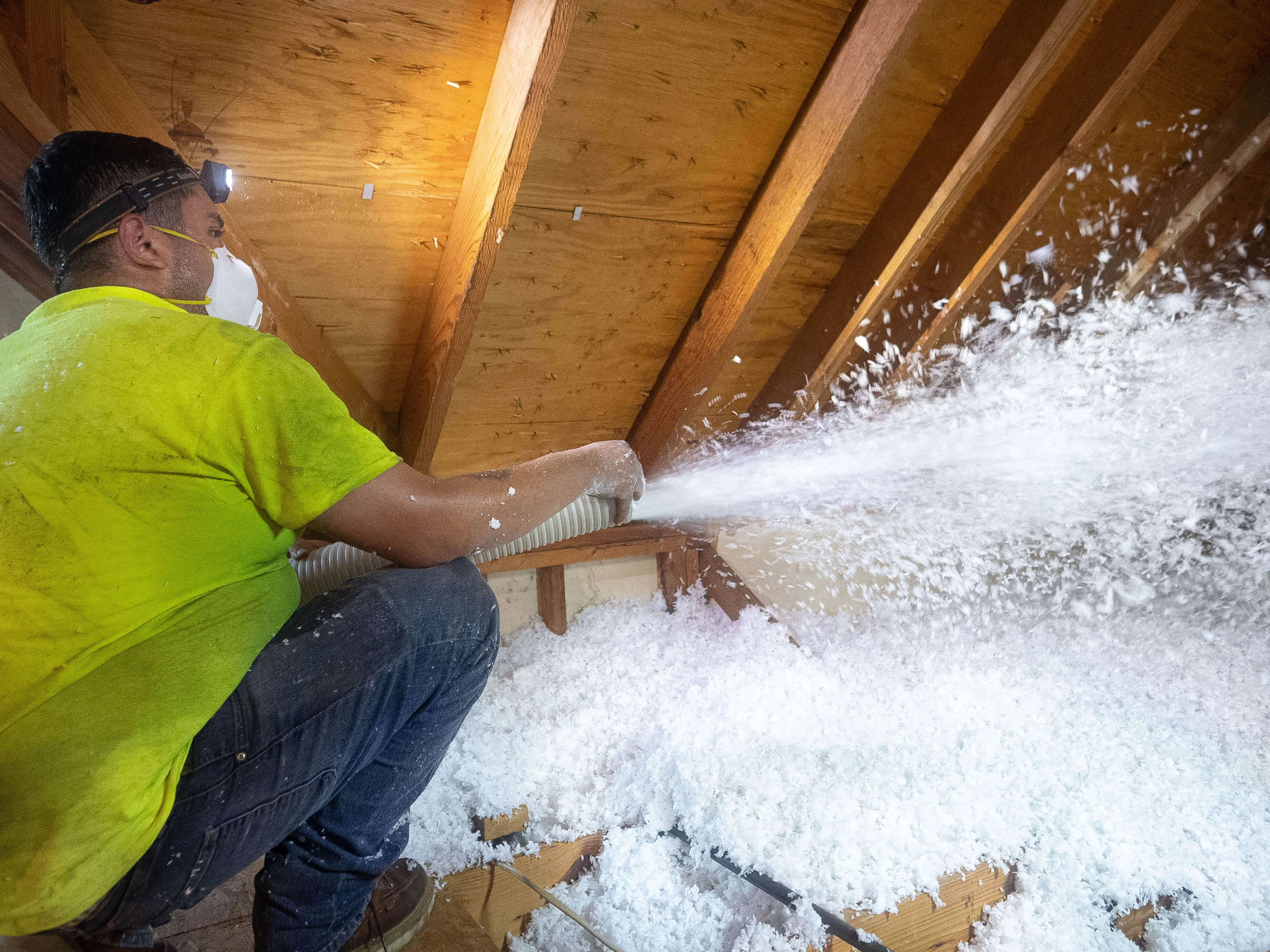 Superior Attic technician blowing fiberglass insulation into an attic