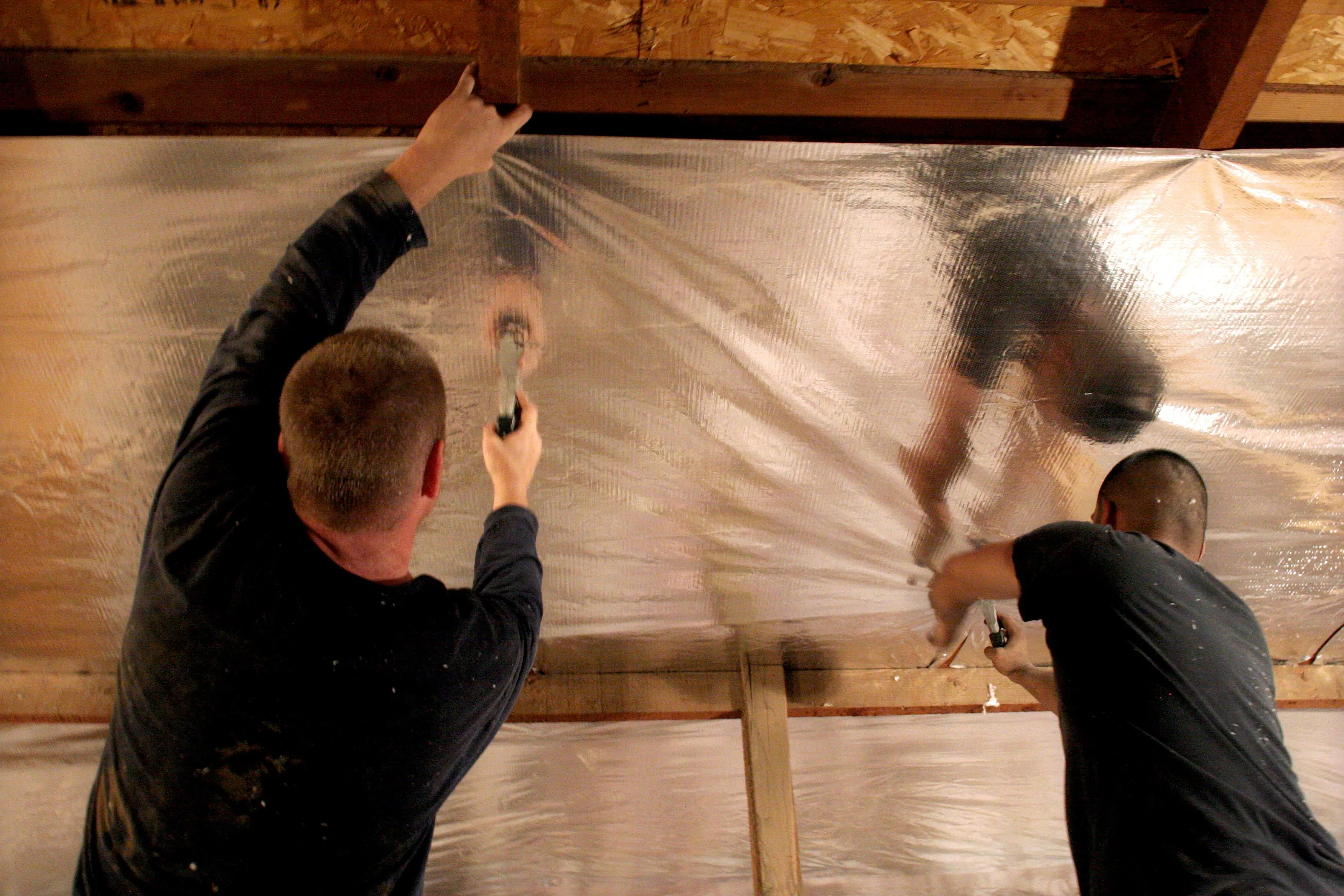 Superior Attic crew hanging radiant barrier on attic joists